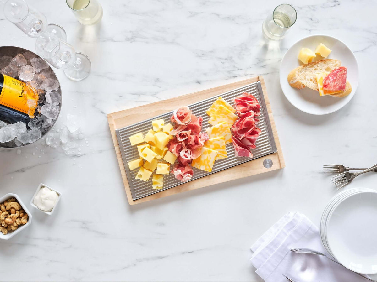ChillTHAT! Platter with assorted cheese and prosciutto, showcasing its refreezable, food-safe aluminum design in a stylish kitchen setting.